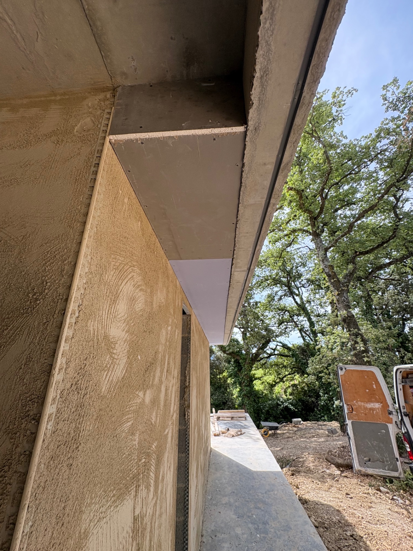 Habillage extérieur en plaque sous débord de toit, enduit gratté ocre